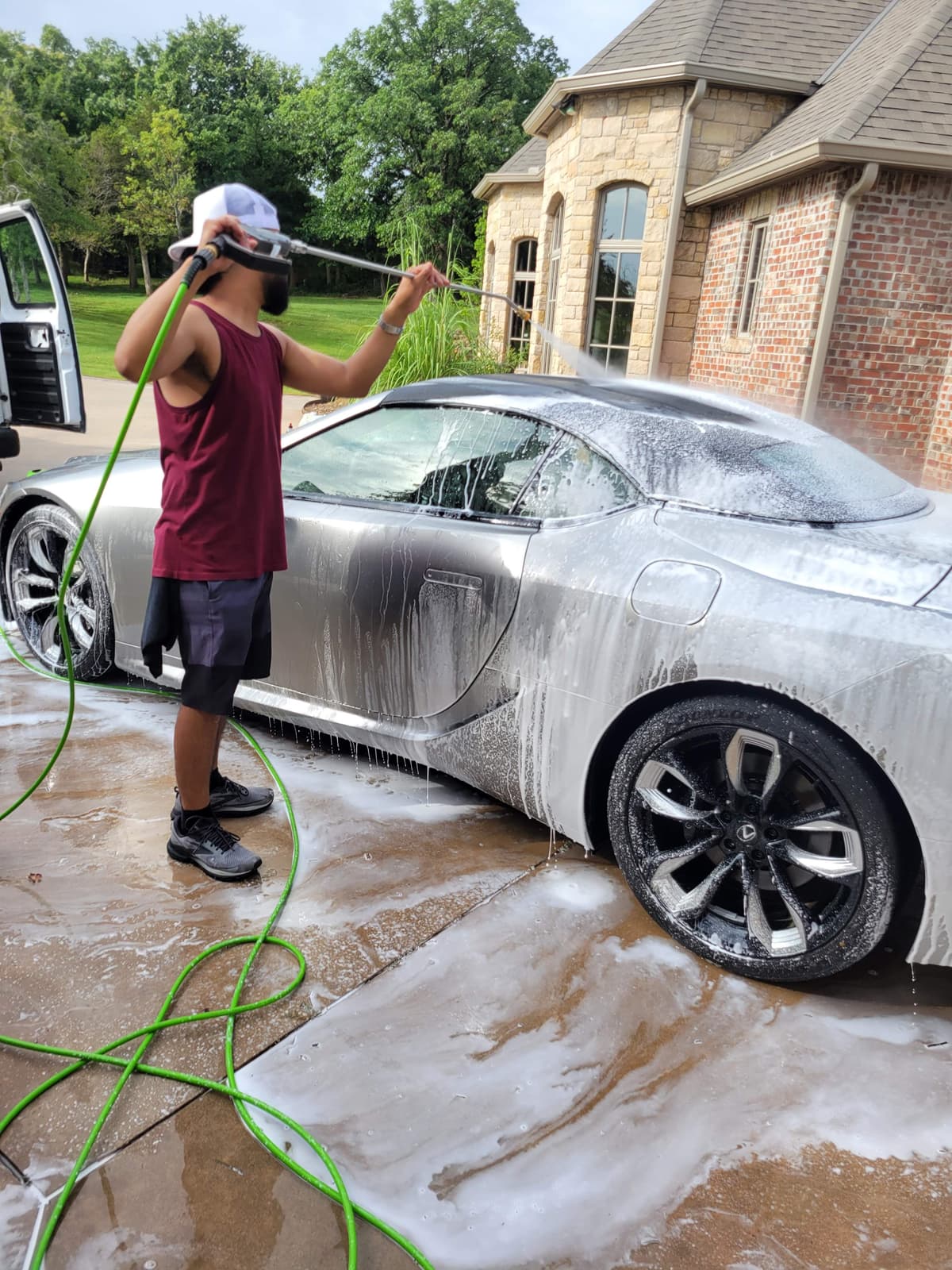 Owner of LXA Mobile Detailing washing a silver sports car